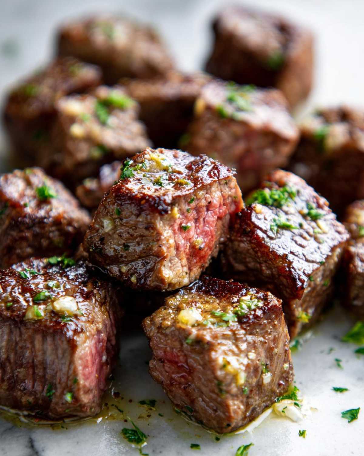 Close-up of perfectly cooked Garlic Butter Steak Bites showing a juicy, medium-rare center and glistening garlic butter sauce.