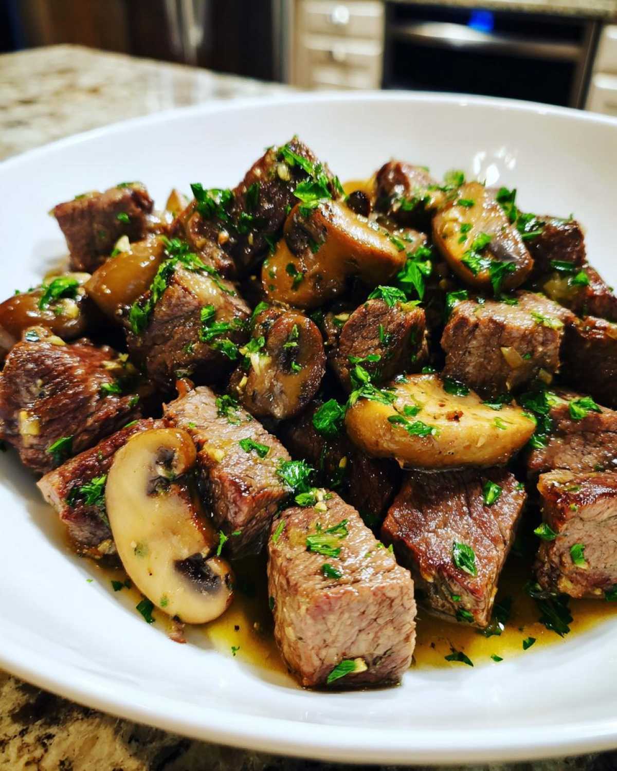 Close-up of juicy Garlic Butter Steak Bites with Mushrooms, glistening in sauce and topped with fresh parsley.