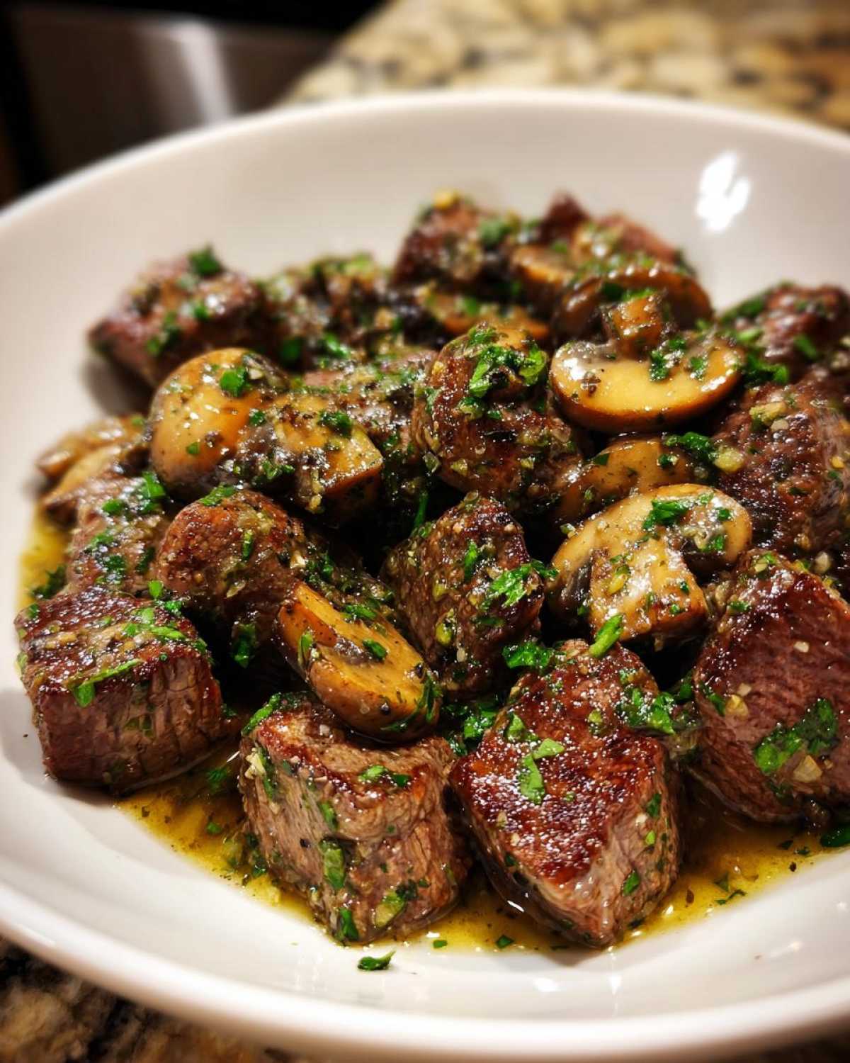 Close-up of tender Garlic Butter Steak Bites with Mushrooms coated in a rich, herbed garlic butter sauce.