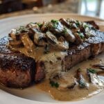 A perfectly seared steak topped generously with creamy mushroom sauce and sliced mushrooms, featuring Garlic Butter Steak.