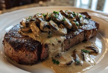 A perfectly seared steak topped generously with creamy mushroom sauce and sliced mushrooms, featuring Garlic Butter Steak.