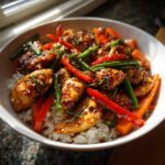 Close-up of a Honey Garlic Chicken Bowl with white rice, glazed chicken pieces, red peppers, and green beans.