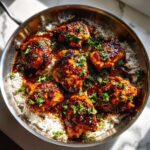 Six pieces of glazed Honey Garlic Chicken Skillet served over white rice in a stainless steel pan, garnished with parsley.