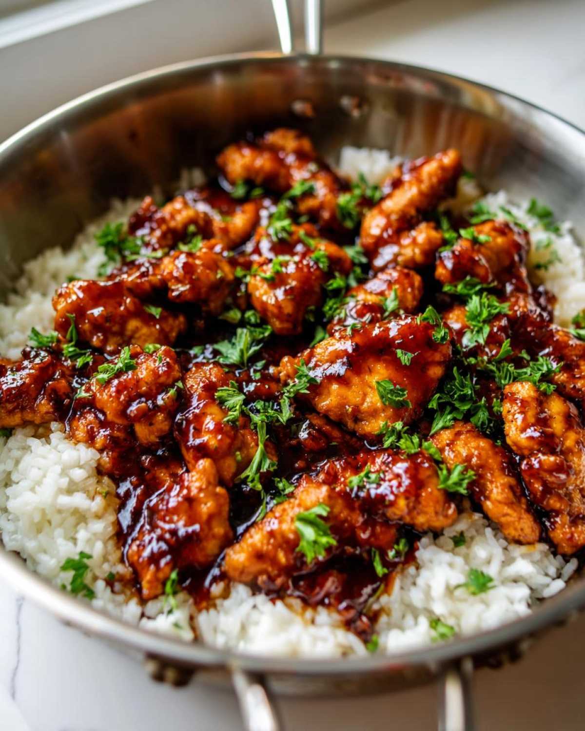 Close-up of Honey Garlic Chicken Skillet with Rice, featuring glazed chicken pieces over white rice, garnished with fresh parsley.