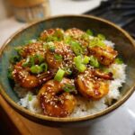 Close-up of a Honey Garlic Shrimp Bowl Quick Dinner served over white rice, topped with sesame seeds and green onions.