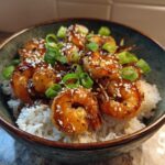 Close-up of a Honey Garlic Shrimp Bowl Quick Dinner featuring glazed shrimp over white rice, topped with sesame seeds and green onions.