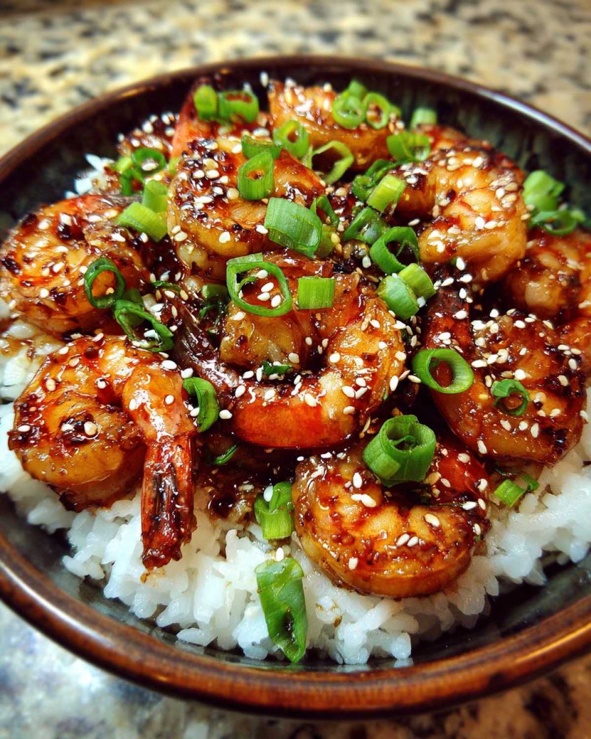 Close-up of a Honey Garlic Shrimp Bowl Quick Dinner featuring glazed shrimp over white rice, topped with sesame seeds and green onions.