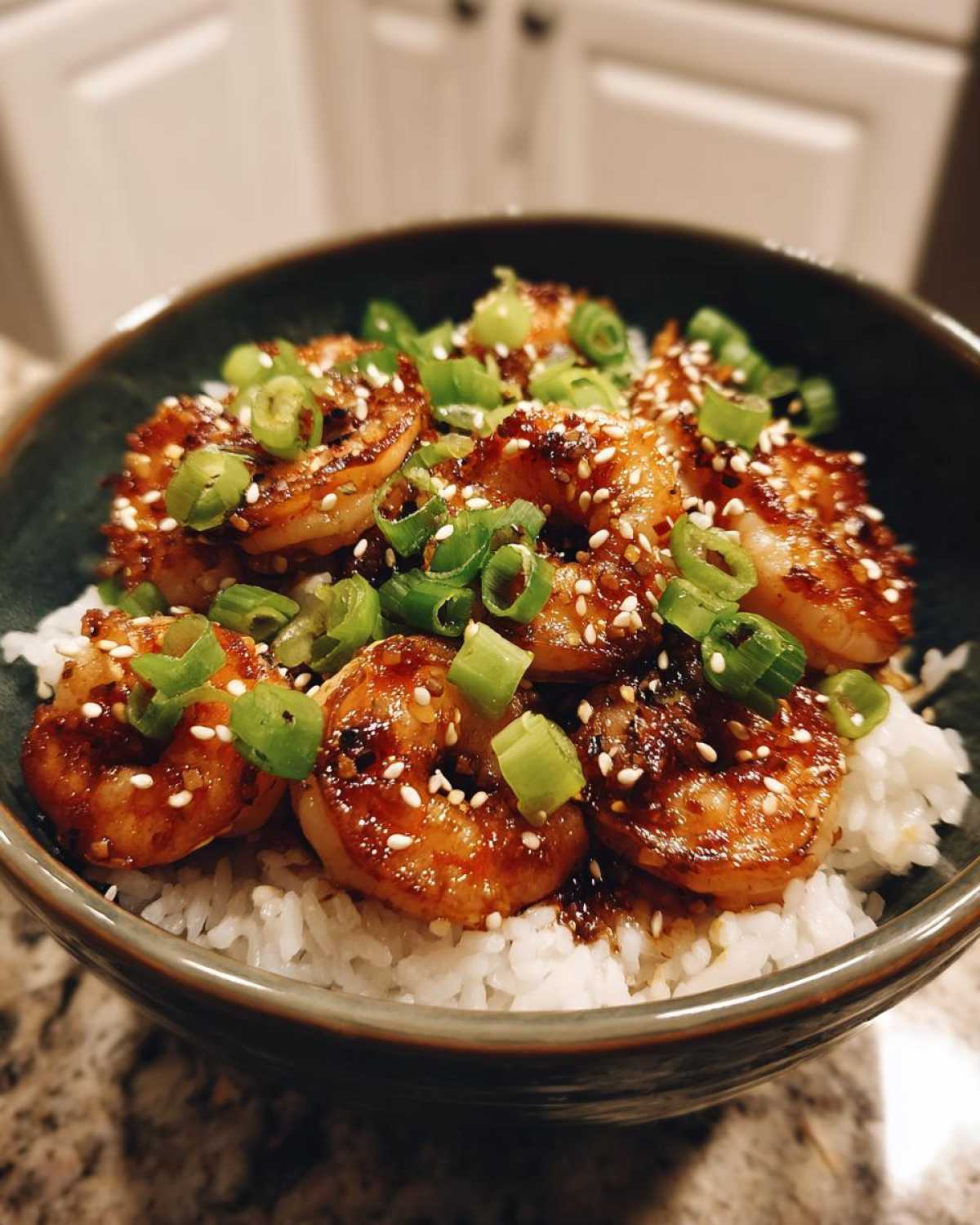 Close-up of a Honey Garlic Shrimp Bowl Quick Dinner featuring glazed shrimp over white rice, topped with sesame seeds and chopped green onions.