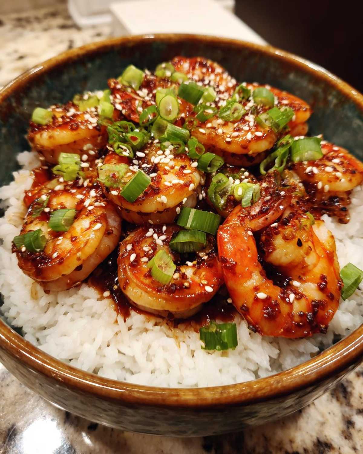 Close-up of a Honey Garlic Shrimp Bowl Quick Dinner featuring glazed shrimp served over white rice and topped with green onions and sesame seeds.