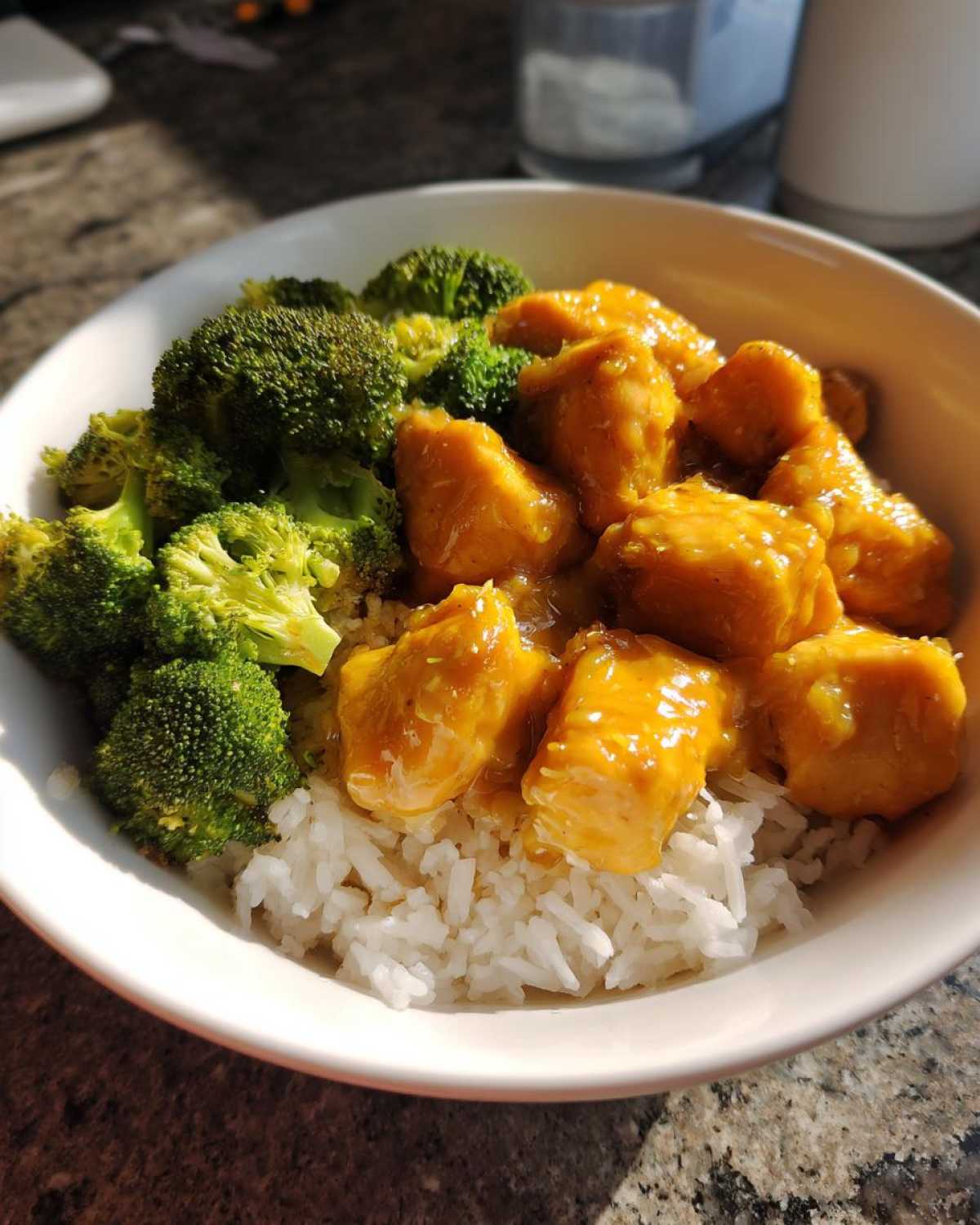 A close-up of a Honey Mustard Chicken Bowl with Rice, featuring glazed chicken pieces and bright green steamed broccoli.