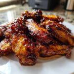 A pile of glossy, caramelized Honey Soy Chicken Wings Crispy Oven Baked stacked on a white plate.