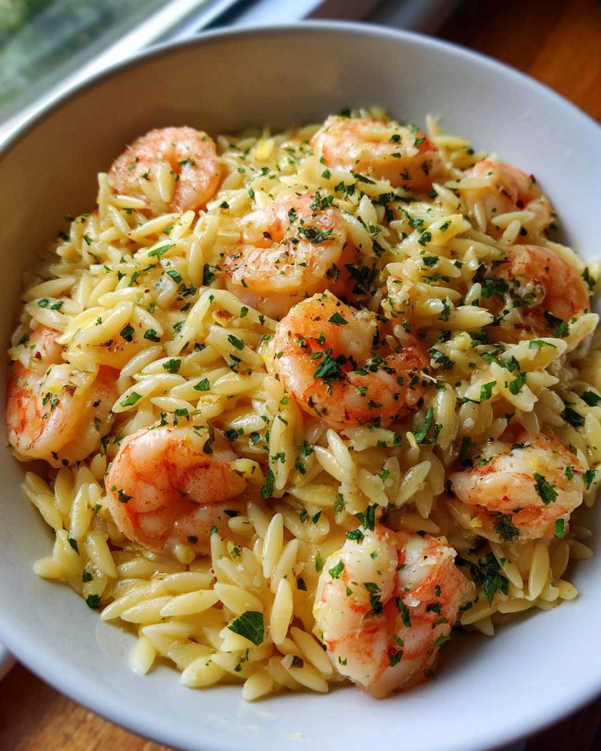 Close-up of a bowl filled with creamy Lemon Garlic Shrimp Orzo, topped with fresh parsley.