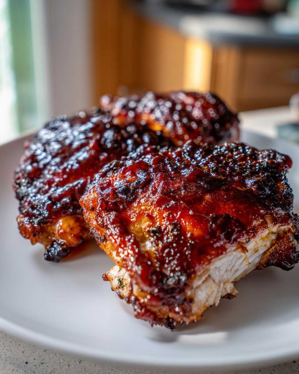 Two pieces of perfectly cooked Sticky BBQ Chicken Thighs with Honey Glaze, showing a dark, caramelized, and glistening exterior.