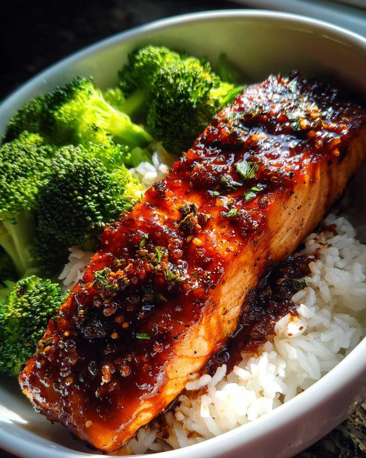 Close-up of a perfectly cooked Sticky Honey Soy Salmon fillet glazed with sauce, served over white rice and steamed broccoli.