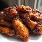 A pile of glistening, crispy Sticky Orange Chicken Wings Crispy Oven Style piled high on a white plate.