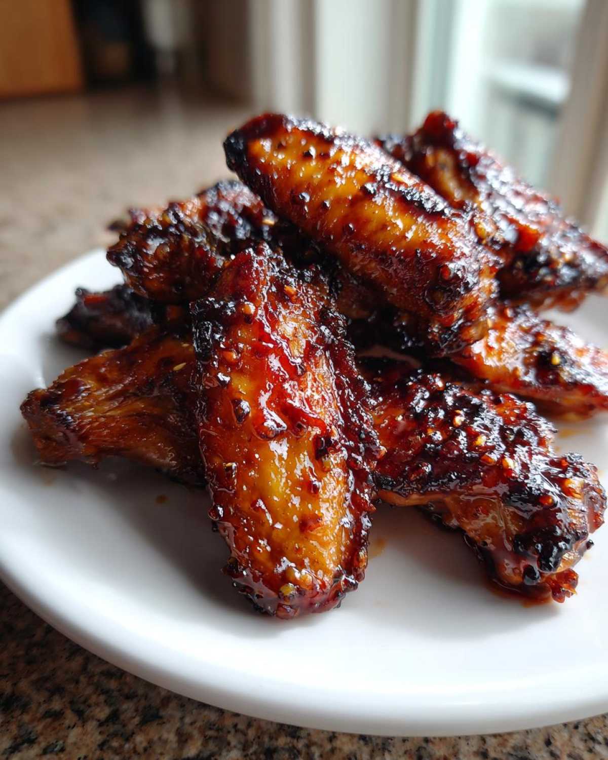 A pile of perfectly cooked Sticky Teriyaki Chicken Wings Crispy Oven Baked, glistening with a thick, dark glaze.