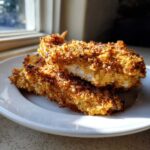 Two pieces of golden brown Air Fryer Chicken with Parmesan Crust stacked on a white plate, showing the crispy texture.