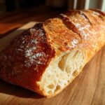A freshly baked loaf of Bakery Style French Bread with a golden, crackly crust, showing an open crumb structure.