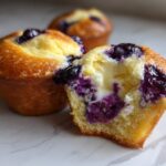 Close-up of a Blueberry Cream Cheese Muffin cut in half showing the creamy center and juicy blueberries.