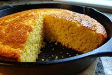 Close-up of golden brown Cast Iron Skillet Cornbread with one slice cut out, showing the moist interior texture.