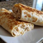 Two halves of a golden-brown Cheesy Garlic Chicken Wraps showing shredded chicken and creamy filling.