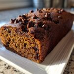 A close-up of a freshly baked Chocolate Chip Vegan Banana Bread loaf topped with melted chocolate chips.
