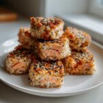 A stack of crispy, pan-fried Salmon Rice Bites topped with black and white sesame seeds, showing the pink salmon center.