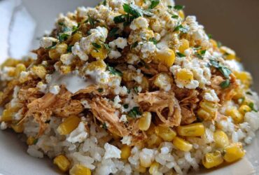 A close-up of the Flavor Street Corn Chicken Rice Bowl featuring shredded chicken, corn, cotija cheese, and cilantro over white rice.
