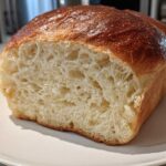 A loaf of Fluffy Yeast Bread Homemade Soft Bread cut in half, showing a light, airy interior and golden-brown crust.