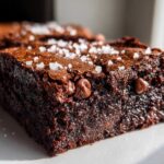 Close-up of a rich, fudgy Brown Butter Brownies slice topped with flaky sea salt and chocolate chips.