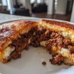 A close-up of Garlic Bread Sloppy Joes cut in half, showing the savory meat filling and melted cheese inside the toasted bread.