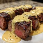 Close-up of perfectly cooked medium-rare Garlic Butter Steak with Parmesan Cream Sauce drizzled over top.