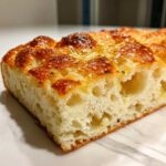 Close-up of a thick slice of airy Garlic Parmesan Focaccia Bread showing its dimpled, golden crust and moist interior.