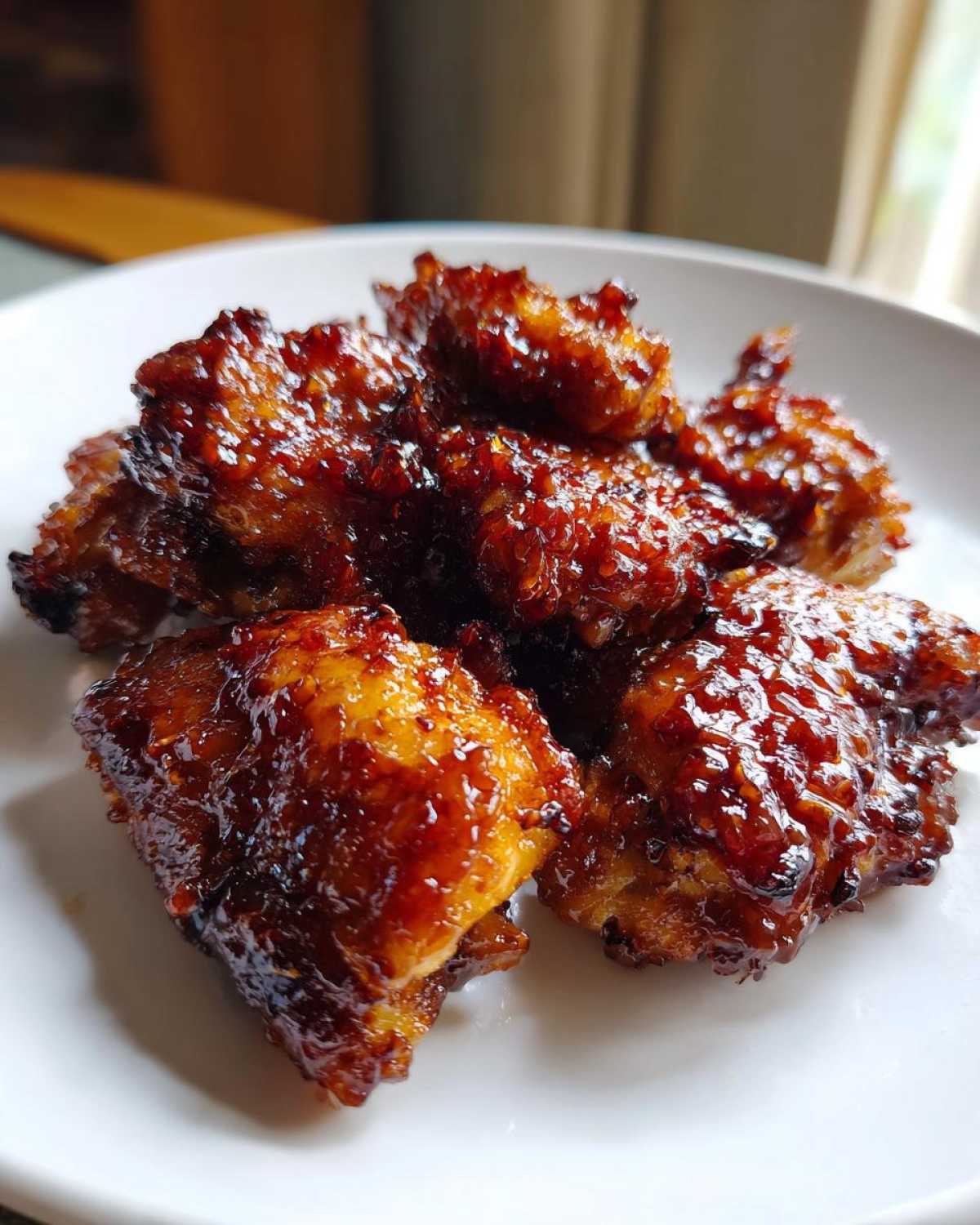 Close-up of crispy, glazed pieces of Honey Garlic Chicken piled on a white plate.