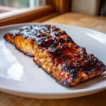 Close-up of a perfectly cooked, glazed Texas Roadhouse Salmon fillet served on a white plate.