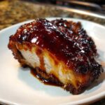 Close-up of a juicy piece of Honey BBQ Chicken coated in thick, glossy sauce.