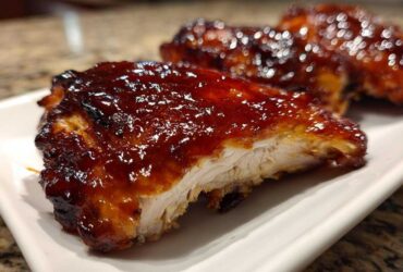 Close-up of a juicy piece of Honey BBQ Chicken, showing the thick, glossy glaze and white interior meat.