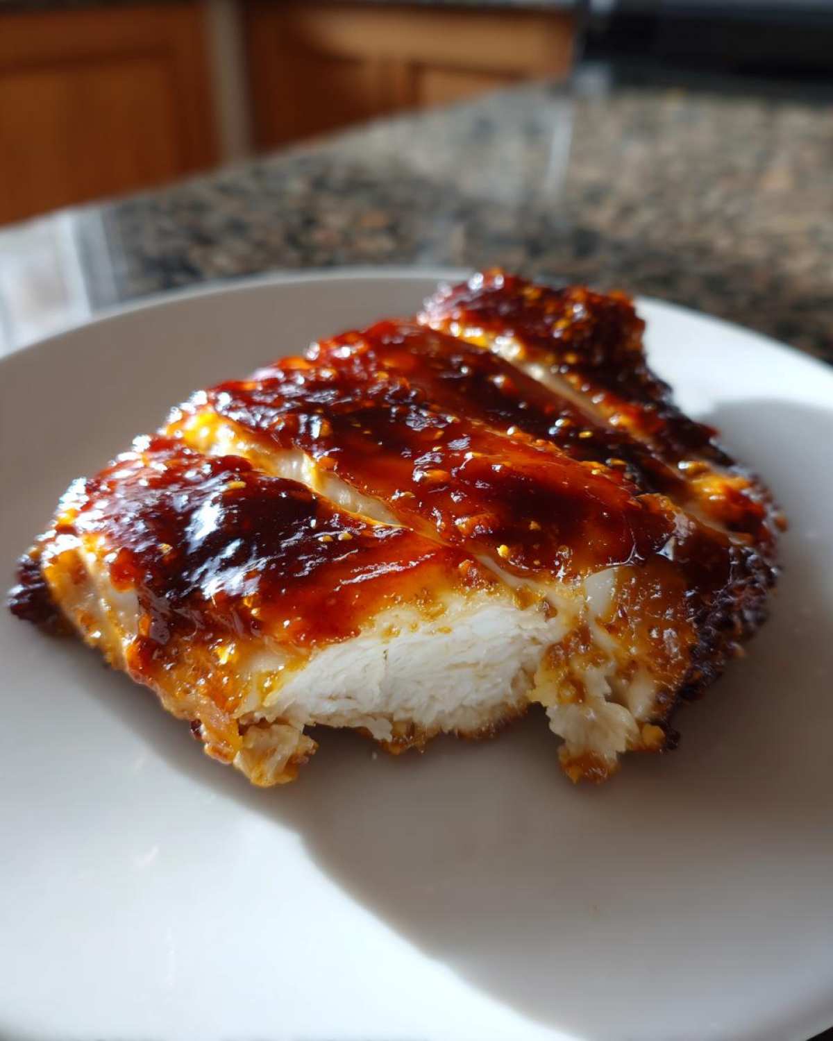 Close-up of sliced Honey BBQ Chicken breast covered in a thick, glossy, dark amber glaze.
