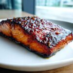 A perfectly cooked fillet of Honey Garlic Glazed Salmon with a dark, shiny glaze and sesame seeds.