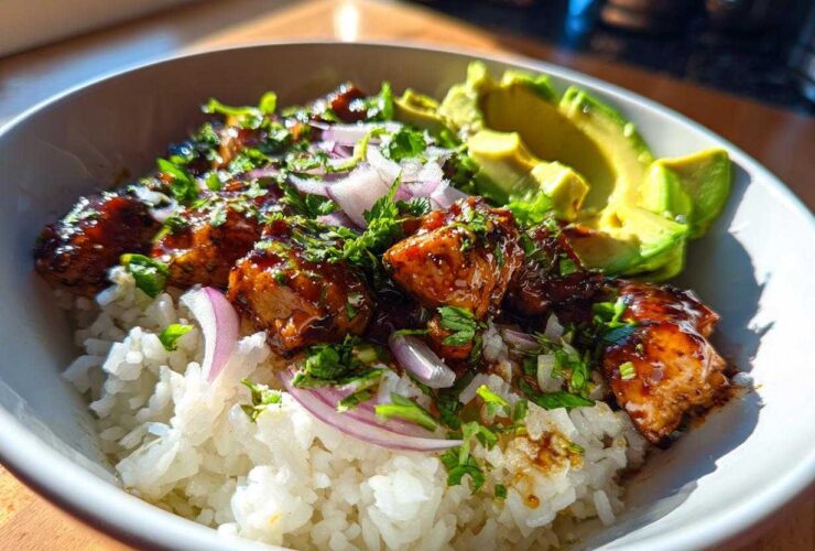 Close-up of a Honey Lime Chicken Avocado Rice Bowl with glazed chicken, white rice, red onion, and sliced avocado.
