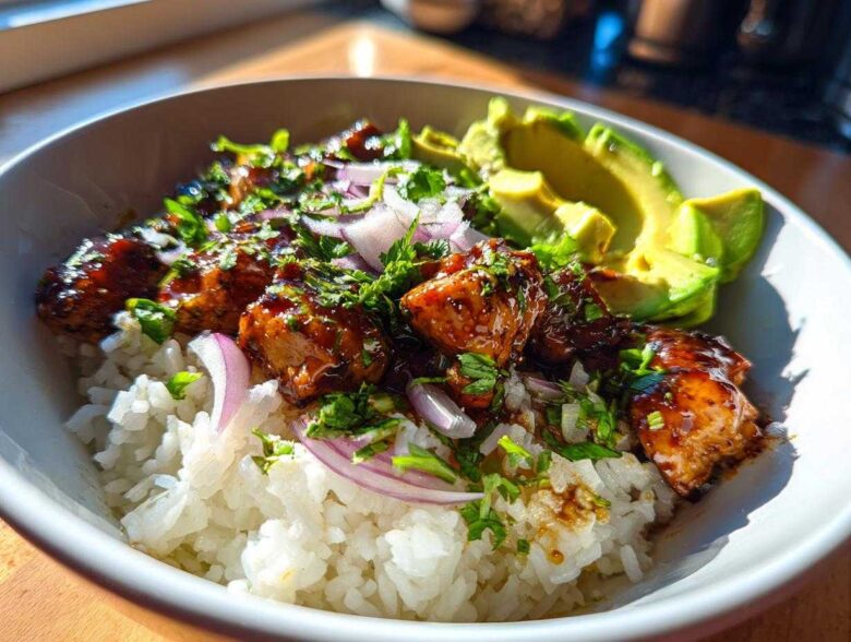 Close-up of a Honey Lime Chicken Avocado Rice Bowl with glazed chicken, white rice, red onion, and sliced avocado.