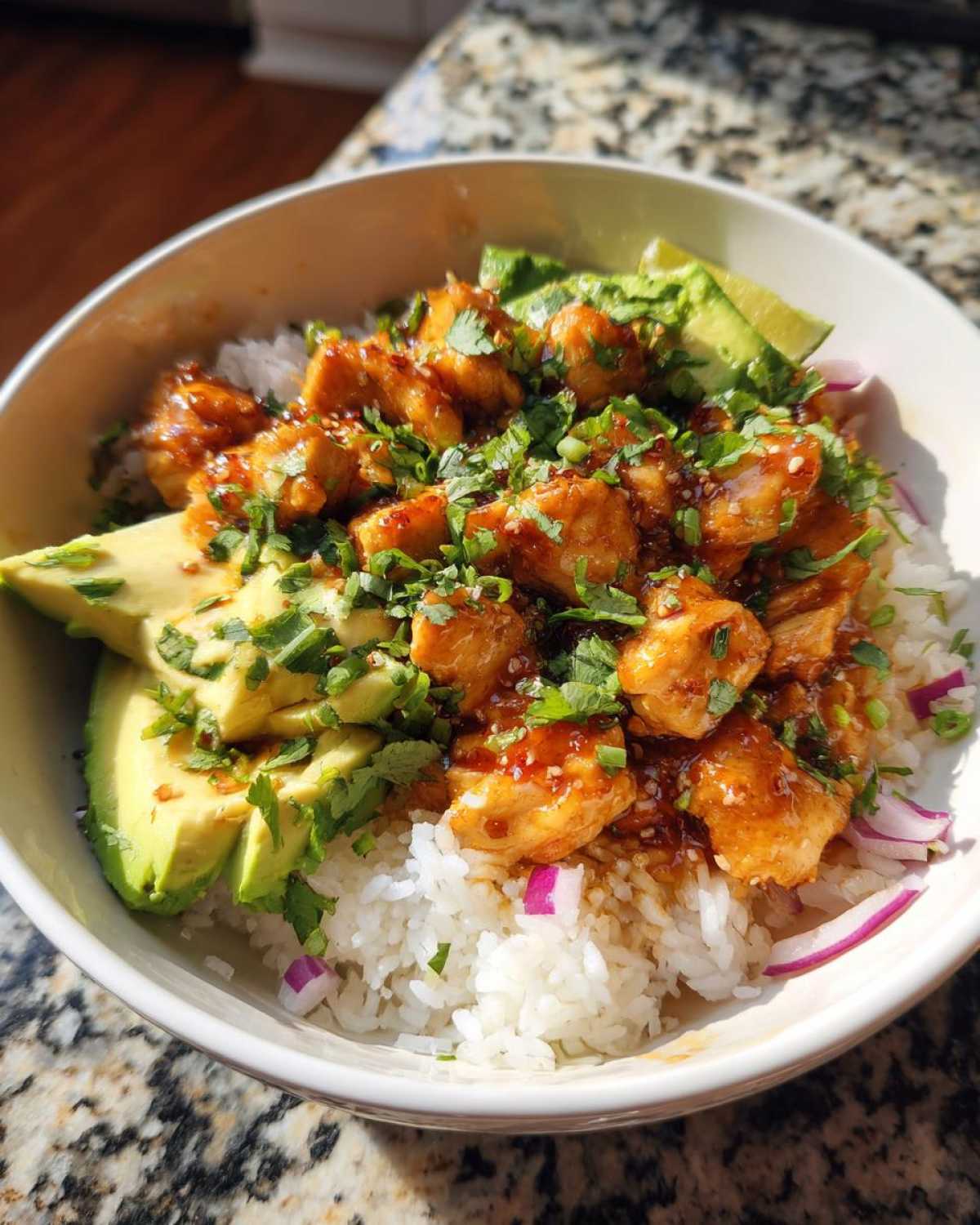 Close-up of a Honey Lime Chicken Avocado Rice Bowl Meal with glazed chicken, sliced avocado, and fresh cilantro.