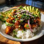 Close-up of a vibrant Honey Lime Chicken Avocado Rice Bowl Meal topped with cilantro and red onion.