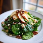 A vibrant Honeycrisp Apple Feta Salad featuring fresh spinach, crumbled feta, pecans, and apple slices drizzled with dressing.