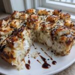 A slice taken out of a round Keto Sushi Bake, topped with seared seafood pieces and sesame seeds.
