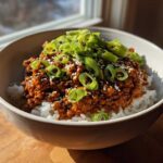 A close-up of a Korean Ground Beef Bowl featuring saucy ground beef served over white rice, topped with sliced green onions and sesame seeds.