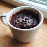 A close-up of a rich, dark Microwave Brownie in a Mug topped with melted chocolate chips.