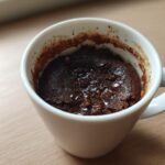 Close-up of a rich, dark chocolate Microwave Brownie in a Mug with melted chocolate chips on top.