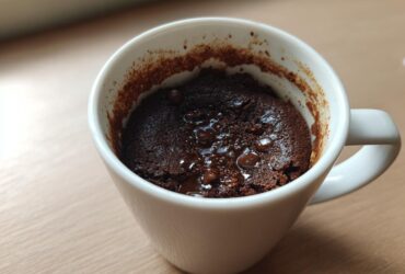 Close-up of a rich, dark chocolate Microwave Brownie in a Mug with melted chocolate chips on top.