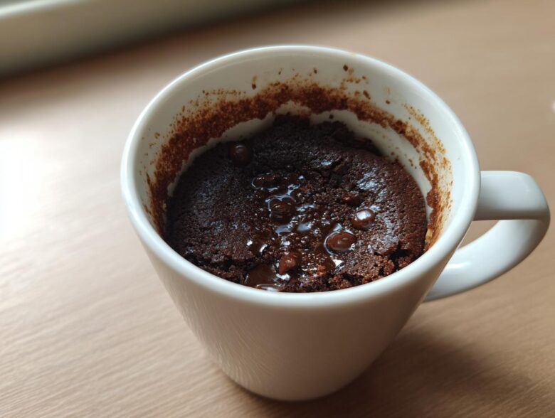 Close-up of a rich, dark chocolate Microwave Brownie in a Mug with melted chocolate chips on top.